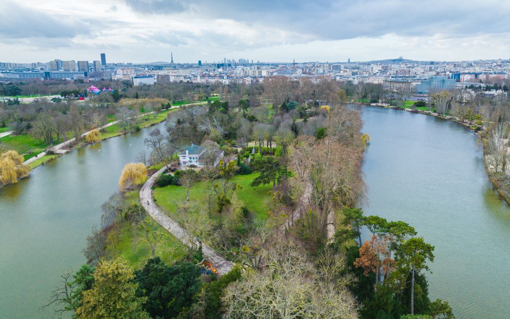 La CPTS Stunning aerial view of a Parisian park with river, trees, and city skyline.