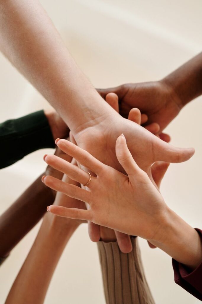 La CPTS A close-up of diverse hands joined together symbolizing teamwork, cooperation, and unity indoors.